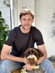 Man in black shirt with a brown dog on his lap.